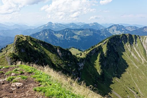 Panoramic view of lush green mountains under a partly cloudy sky, showcasing the natural beauty of the landscape.