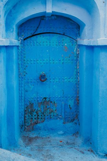 A vertical shot of an old rusty blue door of an aged building in Chefchaouen, Morocco