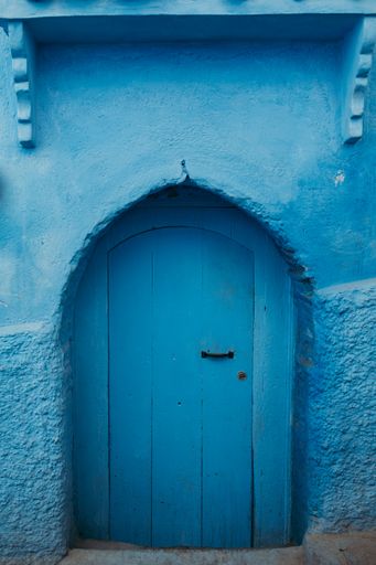 A vertical shot of an old wooden blue door of an aged building in Chefchaouen, Morocco