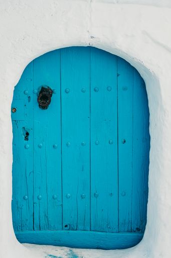 A vertical shot of an old wooden blue door of an aged building in Chefchaouen, Morocco