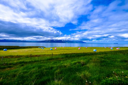 An aerial shot of river in the middle of rocky cliffs and grassy field under a cloudy sky