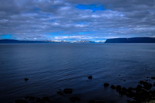 A beautiful shot of a sea and mountains in the distance under a cloudy sky