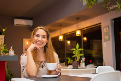 A young female sitting indoors with a cup of coffee