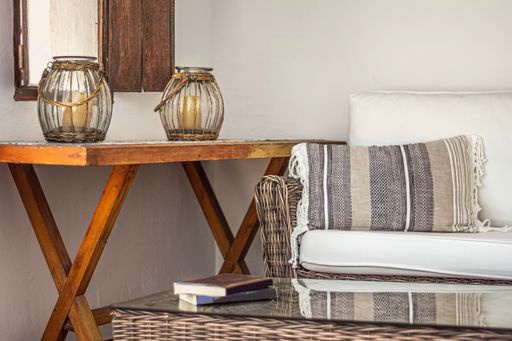 A cozy living room with tables, lamps, a couch, books, and white walls