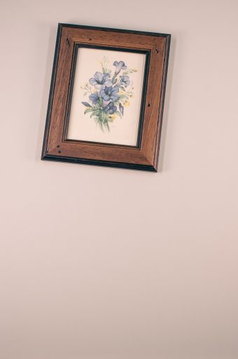 A vertical shot of a framed picture of flowers on a beige surface
