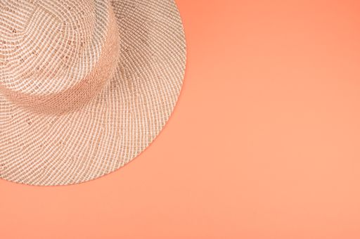 A top view of a straw hat on an orange surface