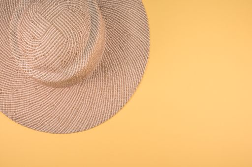 A top view of a straw hat on a yello surface