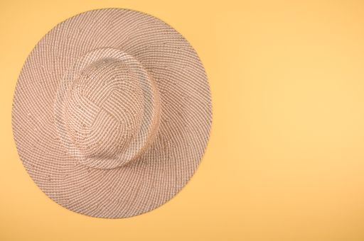 A top view of a straw hat on a yellow surface
