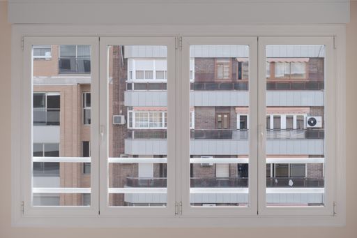Four symmetric white-framed windows with a view of the building in the front