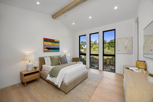 Modern bedroom interior with minimalist decor, featuring a large window and neutral tones, creating a serene and inviting atmosphere.