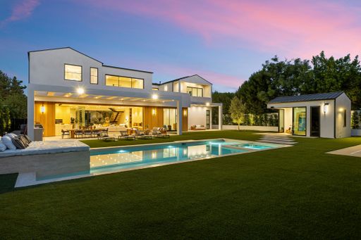 Modern luxury home with a pool and spacious backyard at dusk, featuring elegant architecture and ambient lighting.