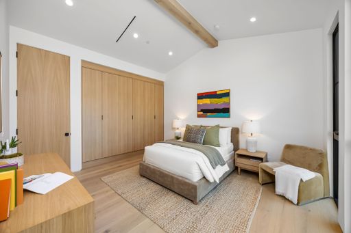 Modern bedroom interior with wooden accents, cozy bed, and stylish decor in a bright, minimalist setting.