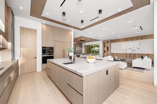 Modern open-concept kitchen and living room with sleek wooden cabinetry and contemporary decor.