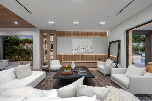 Modern living room with elegant decor, featuring a white sofa, wooden accents, and open views to the garden.