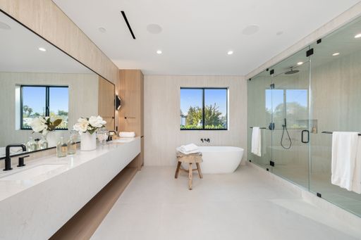 Modern luxury bathroom with a sleek minimalist design, featuring a freestanding tub, glass shower, and large vanity with elegant decor.