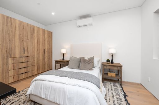 Modern bedroom interior with wooden furniture, neutral tones, and cozy bedding.