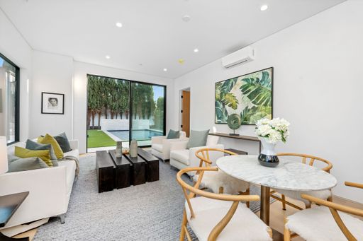 Modern living room with elegant furniture, large windows, and garden view, featuring contemporary decor and a cozy atmosphere.