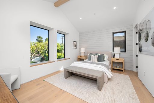 Modern minimalist bedroom with natural light, neutral tones, and stylish decor, featuring large windows and wooden flooring.