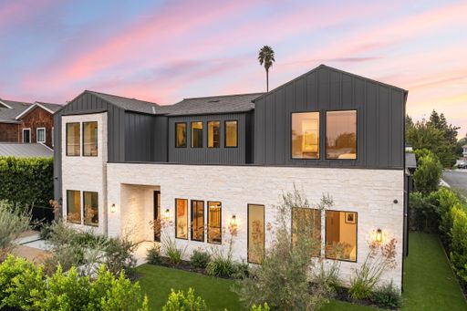 Modern two-story house with a sleek design, large windows, and a beautiful sunset sky in a suburban neighborhood.