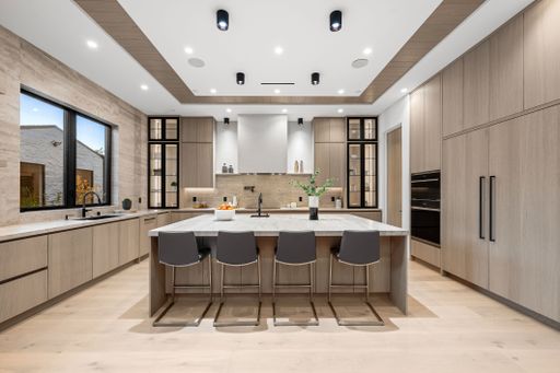 Modern kitchen interior with sleek wooden cabinetry, a large island, and contemporary lighting, showcasing a stylish and functional design.