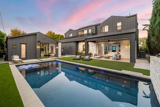 Modern luxury home with sleek design, pool, and spacious outdoor seating area at sunset.