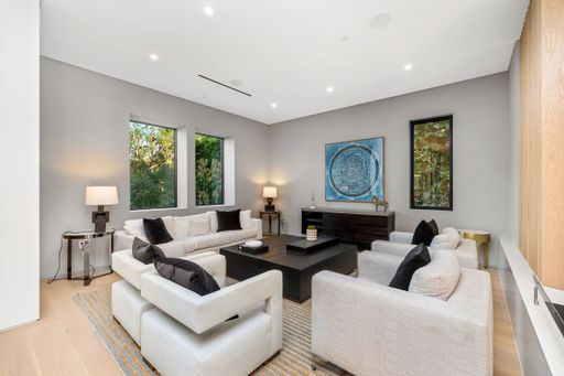 Modern living room with neutral decor, large windows, and stylish furniture, creating a serene and elegant atmosphere.