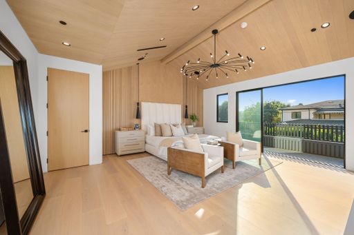 Modern bedroom interior with wooden accents and large windows, featuring stylish furniture and natural light.