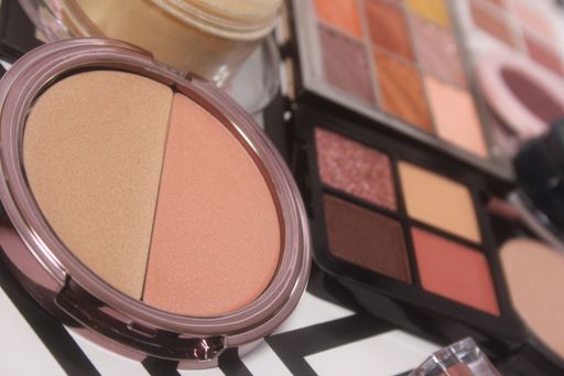 Close-up of makeup palettes with various shades of blush and eyeshadow on a table.
