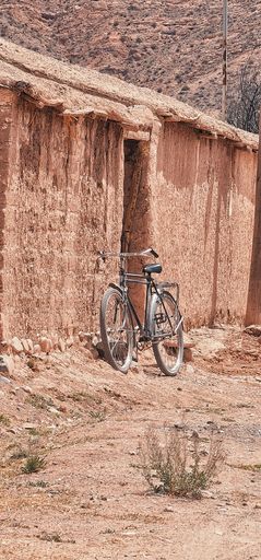 Rustic bicycle leaning against an adobe wall in a desert landscape, capturing the essence of rural simplicity and timeless charm.