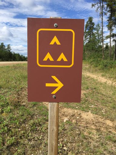 A closeup shot of a group camping sign alongside a road near the fore