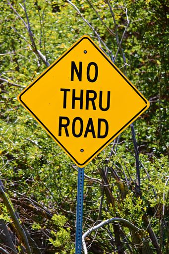 A closeup of a yellow No Thru Road Sign