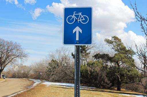 A Bike route ahead sign along a scenic street.