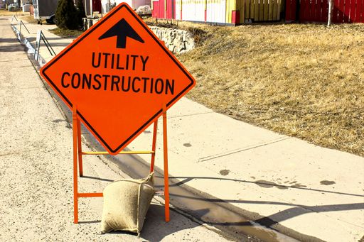 A Temporary utility construction ahead sign beside a sidewalk.