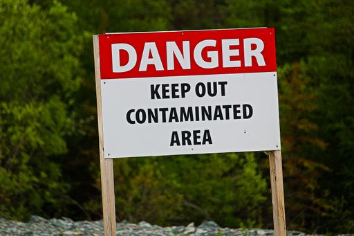 A closeup shot of " a danger keep out of contaminated area" sign
