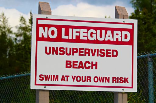 A closeup shot of a "No lifeguard unsupervised beach swim at own risk" sign