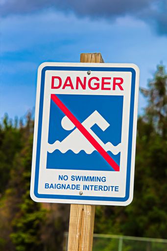 A vertical shot of a "Danger, no swimming" sign in both English and French