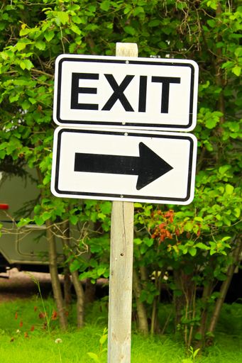 A vertical shot of an exit sign with a directional arrow