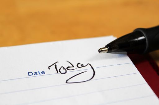 A closeup of the word today written in the notepad with a pen on the side
