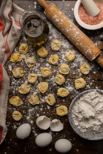 An overhead shot of raw dumplings with ingredients on a wooden table