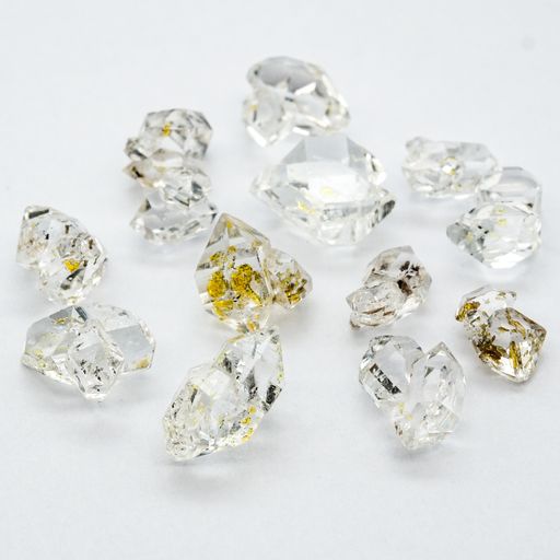Several Herkimer gemstones with oil inside put on a white surface