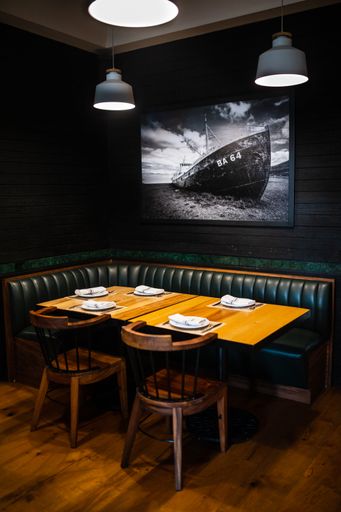 A vertical shot of a cozy modern bar with low hanging bright lamps over a wooden table