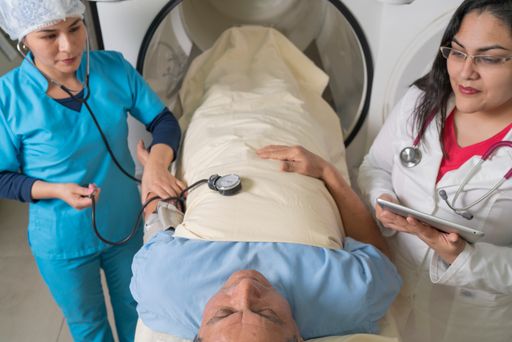 Two doctors taking a patient's blood pressure in front of a hyperbaric treatment machine