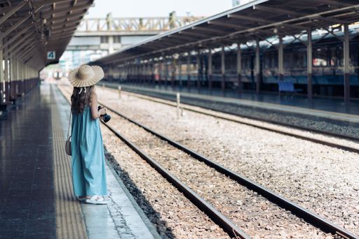 Woman at a Thai station holding a camera, ready to capture moments