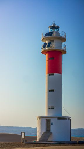 A red and white lighthouse in the desert during daytime