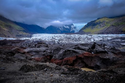 A wide shot of mountains surrounded by white and gray stones under cloudy sky