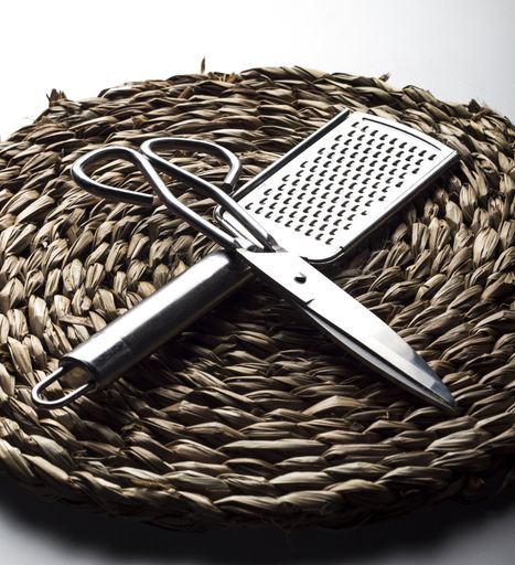 A vertical closeup shot of metal scissors and a scraper on the thatch table