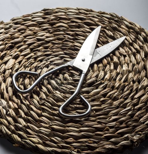 A vertical closeup shot of metal scissors on the thatch table