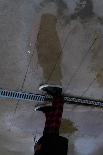 A vertical shot of person's feet standing in the wet street