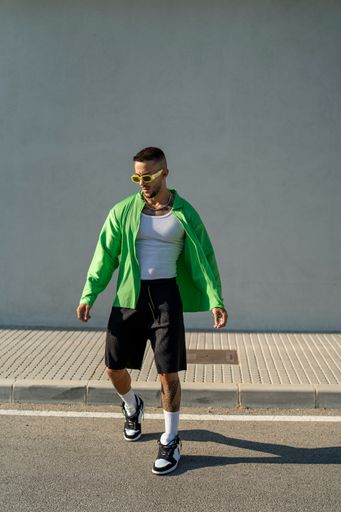 A vertical of a Spanish bearded attractive young male posing in stylish clothes on the street