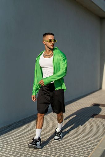 A Spanish bearded attractive young male walking on the sidewalk in stylish clothes